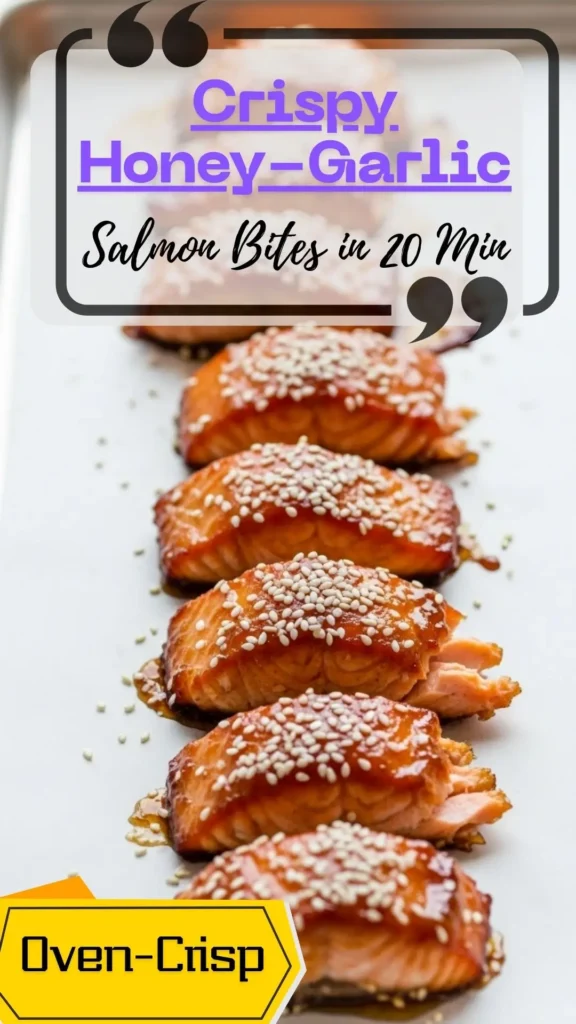Top-down tray of crisp baked salmon bites tossed in glossy honey-garlic glaze, sprinkled with sesame and scallions, with lemon wedges.